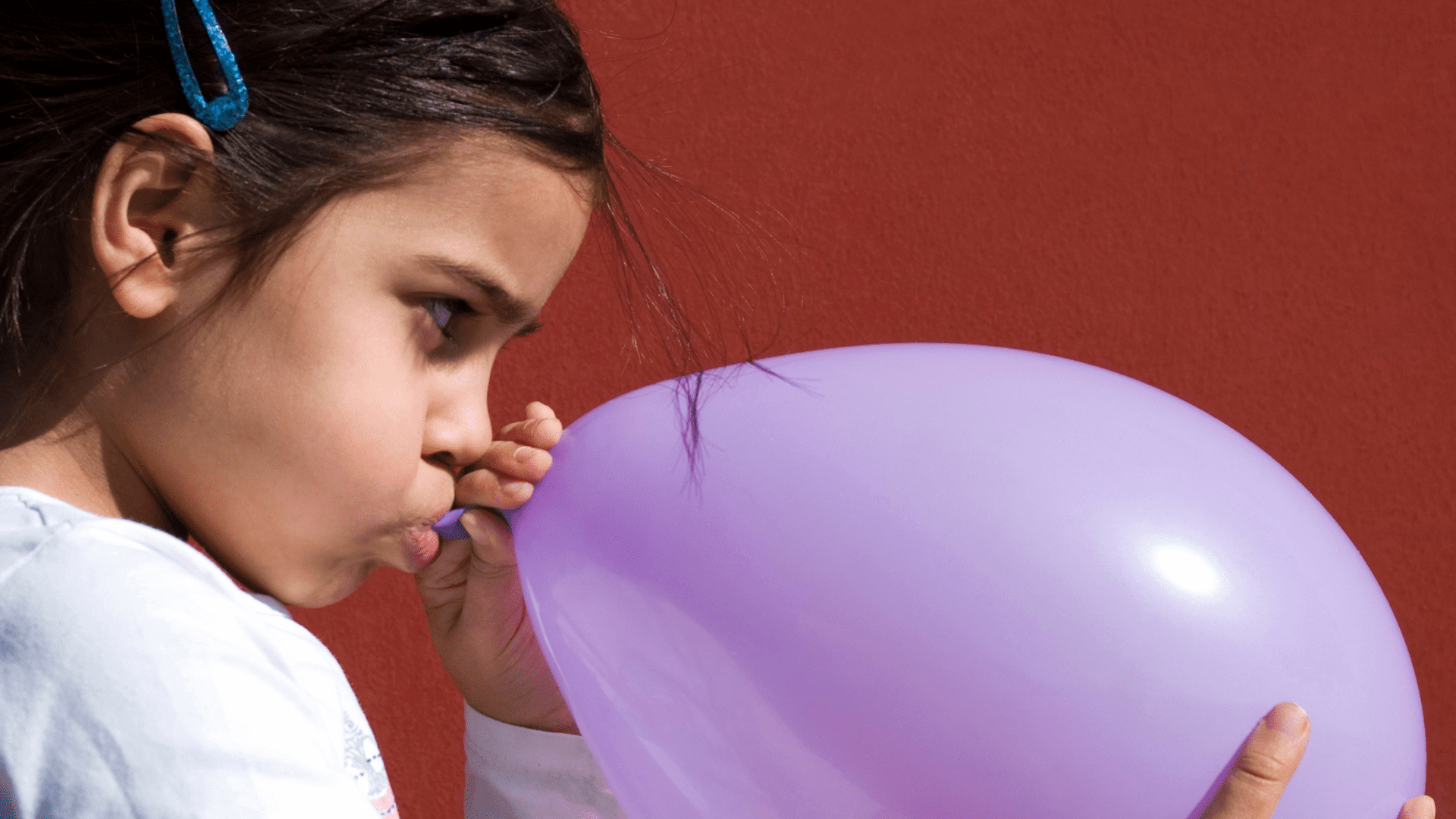 Potential and Kinetic Energy Girl Blowing up a purple balloon