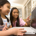 Coding lesson plan two girls looking at a computer and smiling